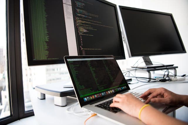 Image of developer workspace showing laptop and computer screens of different sizes.